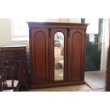 A mid Victorian mahogany triple wardrobe with four drawers to interior