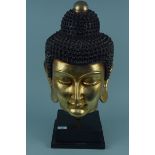 A 20th Century large papier mache Buddha's head with gilded face and mounted on a plinth