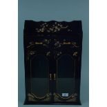 An ebonised two door glazed wall cabinet with two drawers and hand painted decoration