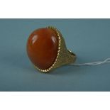 An unmarked yellow metal ring set with large hardstone engraved setting and shoulders, size M 1/2,