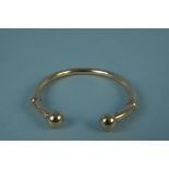 An unmarked yellow metal torque style bangle (slightly misshapen),