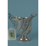 A silver cream jug with embossed floral decoration,