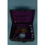 A leather travelling vanity case with part silver mounted contents including mirror and brushes,
