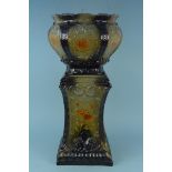A late 19th Century pottery jardiniere on stand on a green ground with brown floral sprays,