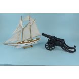 A cast iron model cannon on carriage plus a model top sail schooner