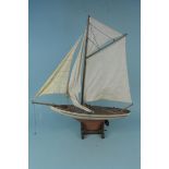 A vintage four sail wooden model yacht on wooden stand,