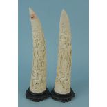 A pair of 20th Century Chinese carved resin tusks on carved hardwood stands