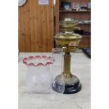A vintage brass based oil lamp with part cranberry glass shade