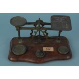 A set of brass postal scales with weights mounted on a walnut base