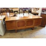 A mid Century G Plan sideboard with two cupboard doors flanked by three drawers and fall cupboard
