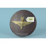 A brass Parachute Regiment badge mounted on wooden shield,