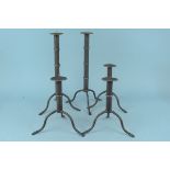 A pair of tall wrought iron pricket candlesticks on tripod supports,