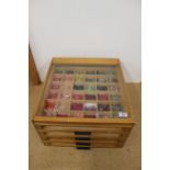 A vintage wood and glass four drawer shop display cabinet with an extensive collection of buttons,