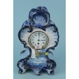 A large late 19th Century blue and white pottery mantel clock in a stylised Rococo case with a hand