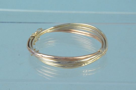 A yellow metal tri-colour bangle, marks rubbed (heavily dented), - Image 1 of 3