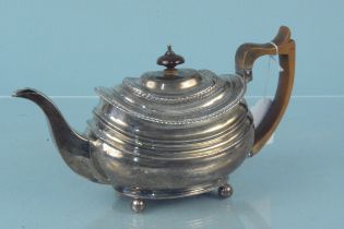 A Georgian silver teapot with wooden handle and engraved crest, hallmarked London 1818,