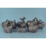 A collection of white metal animal shaped pots