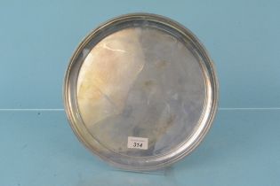 A circular silver salver on four feet, hallmarked Sheffield 1976,