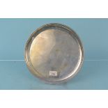 A circular silver salver on four feet, hallmarked Sheffield 1976,