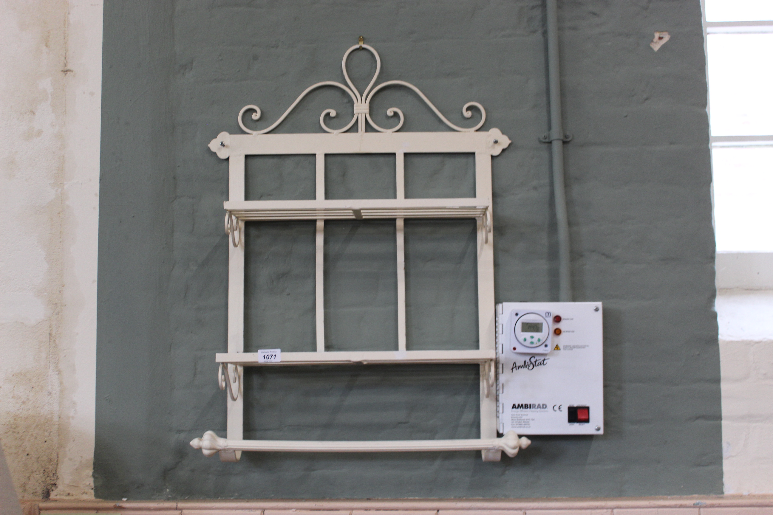 A painted metal wall rack with shelves and towel rail