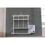 A painted metal wall rack with shelves and towel rail