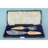 A late 19th Century boxed pair of fish servers with pierced silver plate blades and ivorine handles