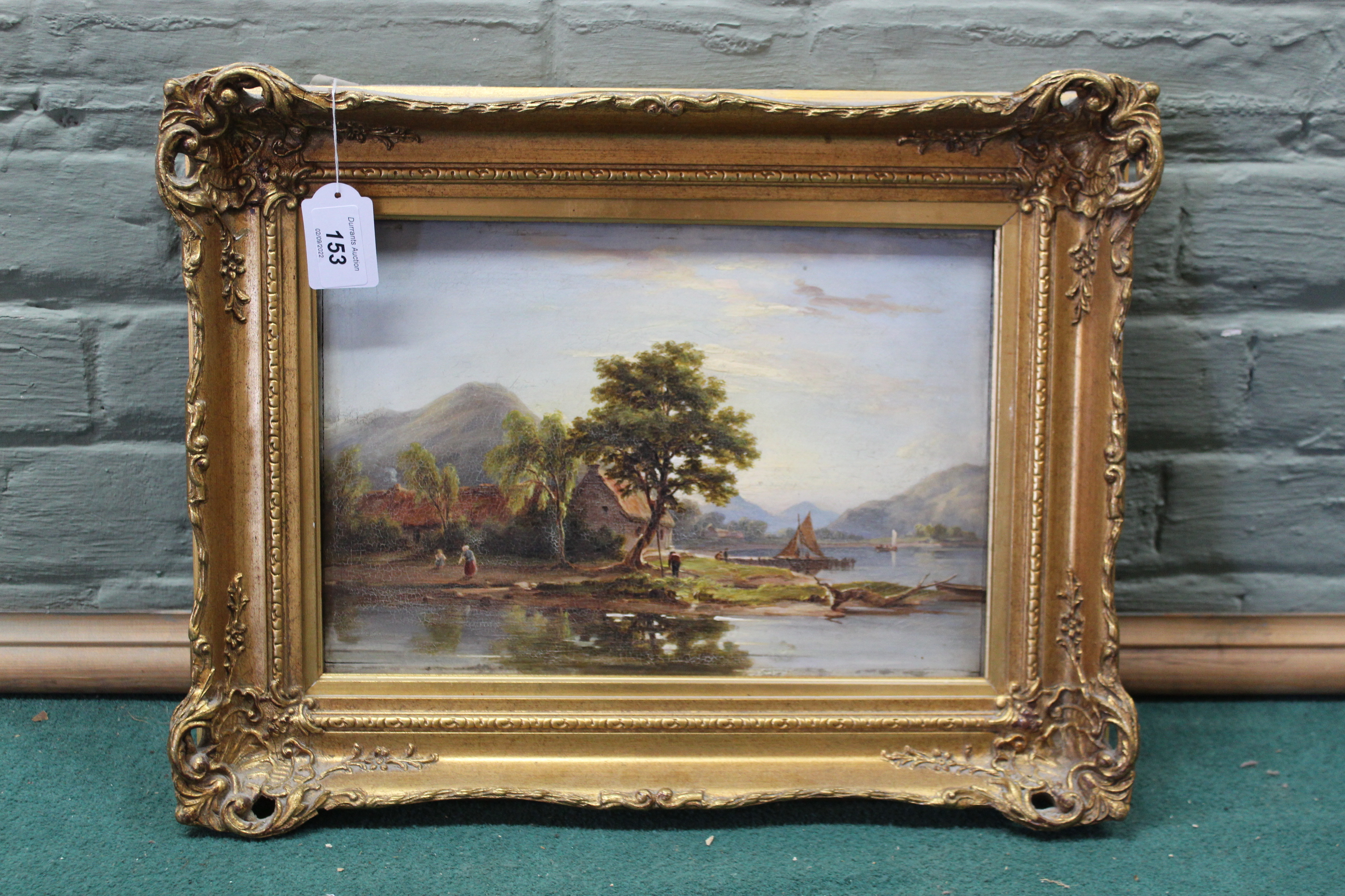 An unsigned gilt framed oil on board of a lake and buildings scene,