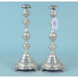 A pair of silver candlesticks with embossed floral and scroll design, hallmarked London 1920,