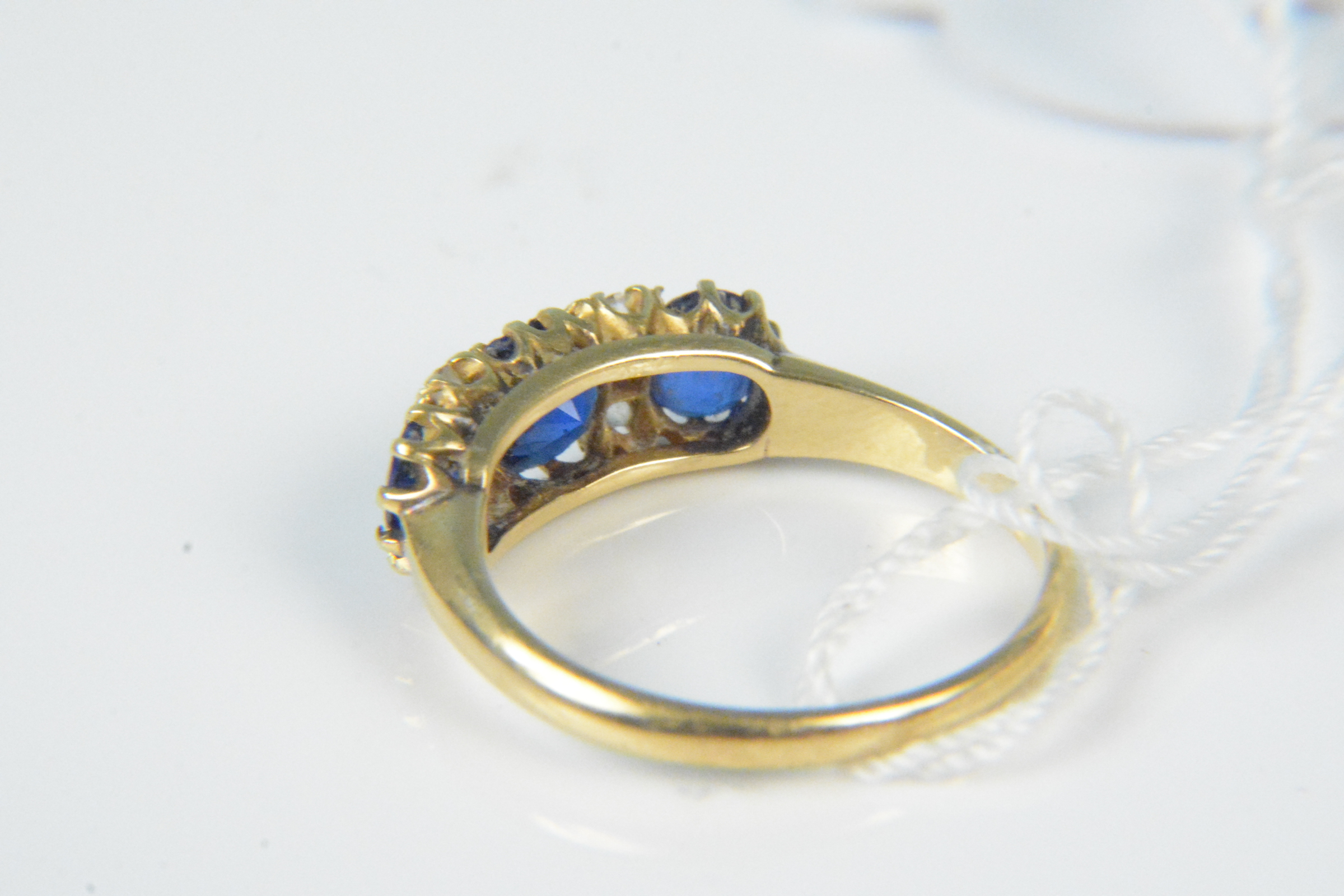 An 18ct gold sapphire and diamond ring, the three claw set sapphires interspaced with small diamond - Image 2 of 3