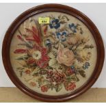 A Victorian mahogany veneered oval framed tapestry of flowers, 32cm diameter and the frame 37.