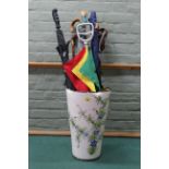 A large ceramic stick/umbrella stand with contents including shooting sticks