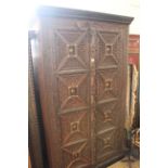 A large Indian hardwood two door cupboard with carved panels and a carved surround