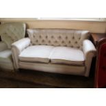 An Edwardian two seater settee with button back pale beige upholstery