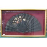 A framed Japanese decorated silk fan with floral patterns and wooden black lacquered handle