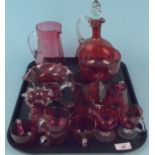 A cranberry glass claret jug, four smaller jugs,