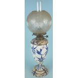An early 20th Century ceramic based oil lamp decorated with birds,