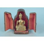 A brass Buddha in a leather presentation case