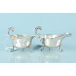 A pair of silver sauce boats with wavy edge detail on three hoof feet, hallmarked Birmingham 1936,
