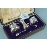 A cased three piece cruet set with associated spoons,