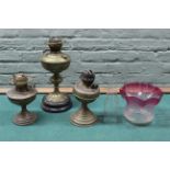 Three brass oil lamp bases plus a cranberry glass shade