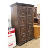 A large Indian hardwood two door cupboard with carved panels and a carved surround