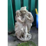 A weathered concrete garden statue of two figures in a warm embrace