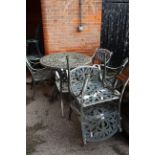 A large metal garden table with six armchairs
