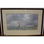 A framed watercolour of Thames barges off the Essex coast with a headland village in the background,