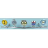 Five vintage car badges mounted on a metal bar, includes Scimitar Drivers club,