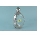 A shaped glass decanter with white metal overlay and lid,
