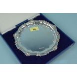 A contemporary silver circular salver on three claw and ball feet with shell decorated border,