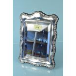 A silver easel backed mirror of shaped floral decorated design, hallmarked Mappin & Webb 1993,