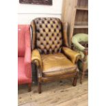 A 20th Century button back brown leather wing armchair