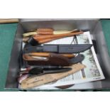 A small metal box containing nine various knives with their sheaths and some empty sheaths